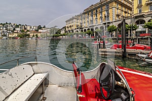 Funny red racing car shaped boats on Lake Lugano, Switzerland, with the city in the background