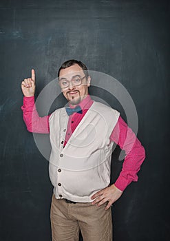 Funny retro style businessman or teacher having idea and finger up on blackboard