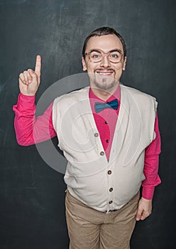Funny retro style businessman or teacher having idea and fingers up on blackboard