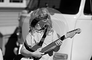 Funny rock child with guitar. Little boy in sunglasses. Kids music concept. Child musician playing the guitar like a