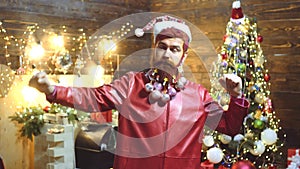 Funny Santa - bearded hipster. Happy modern bearded Claus. Close up face of comic man with decorated beard and santahat