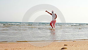 Funny Santa Claus. Father Christmas, in sunglasses and flippers, having fun in the sea water near sandy beach. Santa
