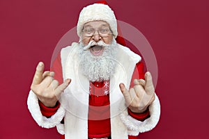 Funny Santa Claus wearing costume showing horns isolated on red background.