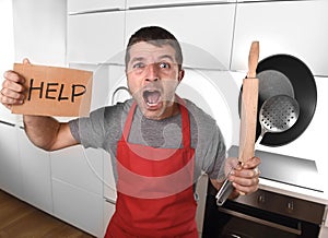 Funny scared man holding pan wearing apron at kitchen asking for help