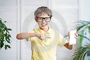 Funny schoolboy with glasses points at the white screen of his mobile phone