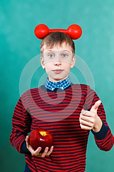 Funny schoolboy with red dumbbell and apple showing thumbs up