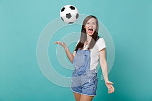 Funny screaming young girl football fan cheer up support favorite team throwing up soccer ball isolated on blue
