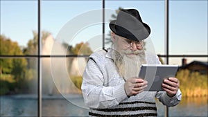 Funny senior man playing game on tablet pc.