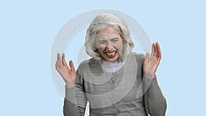 Funny senior woman is laughing on blue background