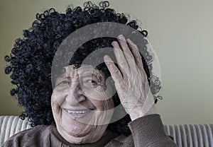 Funny senior woman wearing curly black wig
