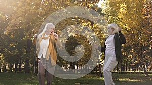 Funny senior women enjoying weather, dancing and having fun in warm autumn park