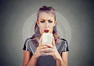 Funny shocked scared woman looking at phone seeing bad news photos message with disgusting emotion on face