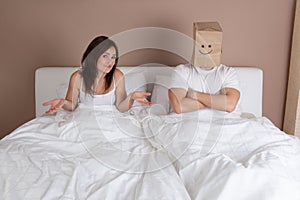 Funny situation in bed. Man with paper bag over head