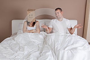 Funny situation in bed. Woman with paper bag over head