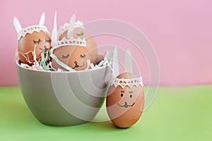 Funny sleep easter bunnies eggs in bowl on pink paper background with copy space. Happy Easter concept.