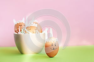 Funny sleep easter bunnies eggs in bowl on pink paper background with copy space. Happy Easter concept.