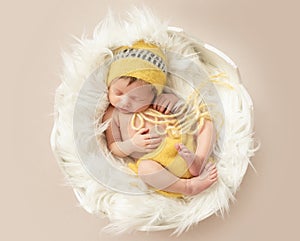 Funny sleeping baby in yellow romper on round cot
