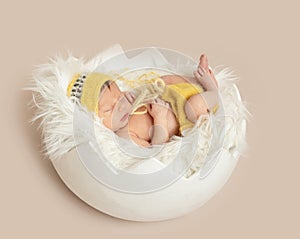 Funny sleeping baby in yellow romper on round cot