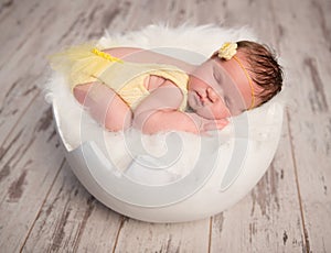 Funny sleeping baby in yellow romper on round cot