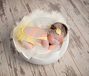 Funny sleeping baby in yellow romper on round cot