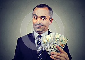 Funny sly business man holding looking at money dollar banknotes