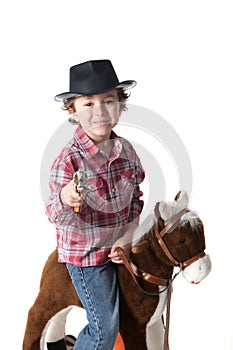 Funny small cawboy with red plaid shirt riding a play horse