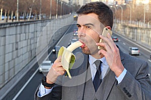 Funny smiley businessman holding a banana while calling by phone