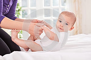 Funny smiling baby gymnastic practice with mother