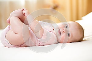 Funny smiling baby infant girl playing with her feet