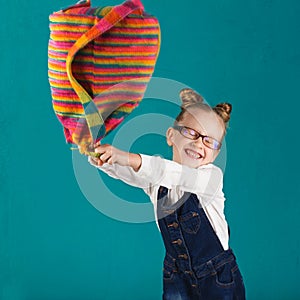 Funny smiling little girl with big backpack jumping and having f