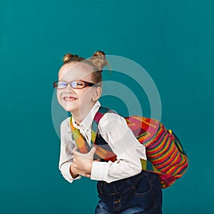 Funny smiling little girl with big backpack jumping and having f