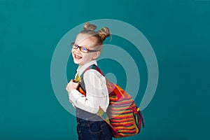 Funny smiling little girl with big backpack jumping and having f