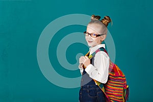 Funny smiling little girl with big backpack jumping and having f