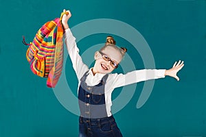 Funny smiling little girl with big backpack jumping and having f