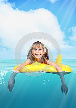 Funny smiling little girl with diving glasses floating inflatabl