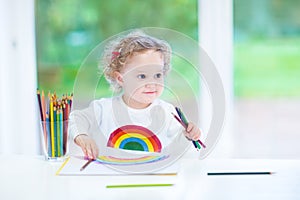 Funny smiling toddler girl drawing a rainbow