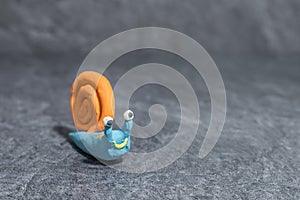 Funny snail made of play dough in front of grey background