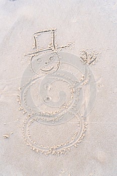 A funny snowman in a top hat painted on the sand of the beach.