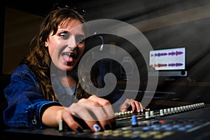 Funny in sunglasses and jeans behind the mixer in the recording studio. Crazy sound engineer at the mixing desk in the music