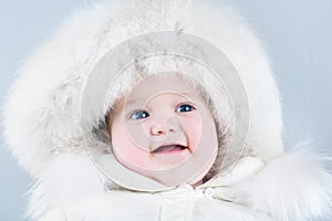 Funny sweet baby girl wearing a big fur hat