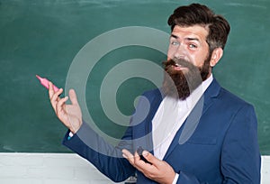 Funny teacher or professor near blackboard. Man teaching near chalkboard in classroom. Thinking serious mature teacher