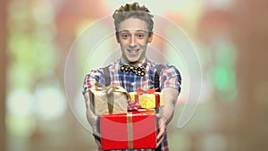 Funny teen guy giving present boxes.