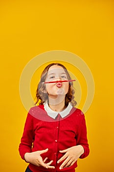 Funny teen school girl make mustache on her face with red pencil,