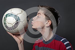 Funny teenage boy is kissing a soccer ball