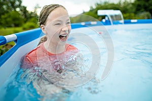 Funny teenage girl having fun in outdoor pool. Child learning to swim. Kid having fun with water toys. Family fun in a pool.