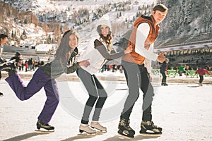 Funny teenagers girls and boy skating outdoor, ice rink