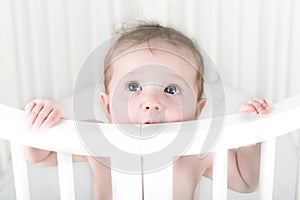 Funny teething baby biting on its crib