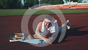 Funny tired sweaty young man performs push-ups, falls tired, quenches his thirst with beer. The concept of losing weight