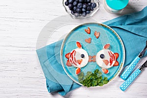 Funny toasts in a shape of kissing fishes, sandwich with cream cheese and berries, milk and blueberries, food for kids idea