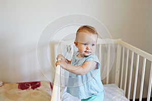 Funny toddler baby girl standing in her white bed